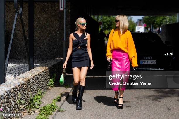 Thora Valdimars wearing black top, mini skirt, knee high boots, green bag & Jeanette Friis Madsen wearing orange knit, pink skirt with slit, platform...
