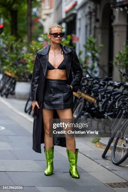 Guest is seen wearing black leather coat, bra, skirt, metallic green cowboy boots outside Ræburn during Copenhagen Fashion Week Spring/Summer 2023 on...