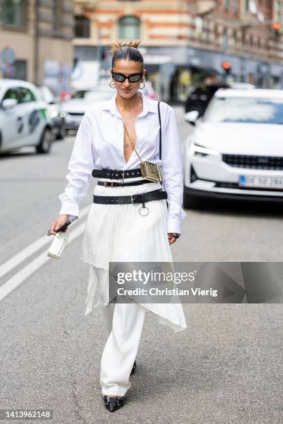 Guest is seen wearing pleated asymmetric skirt, belt, white button shirt, Dior bag outside Ræburn during Copenhagen Fashion Week Spring/Summer 2023...