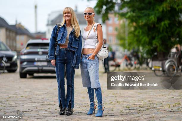 Jeanette Madsen wears a beige ribbed halter-neck / cropped tank-top, a navy blue denim buttoned / cropped jacket, high waist matching bicolored denim...