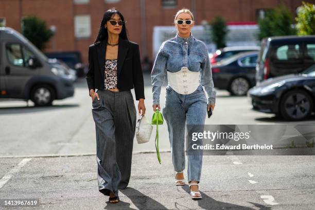 Pornwika Spiecker wears black cat eyes sunglasses, a black chain necklace, a black with embroidered silver sequined V-neck t-shirt, a black cropped...