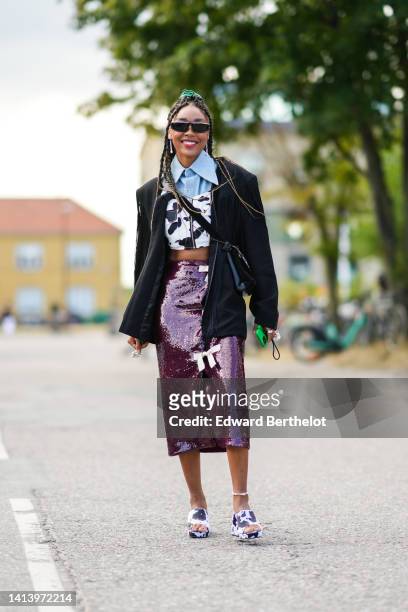 Guest wears black sunglasses, white pearls pendant earrings, a blue denim cropped shirt, a black and white cow print pattern / zipper / square-neck /...