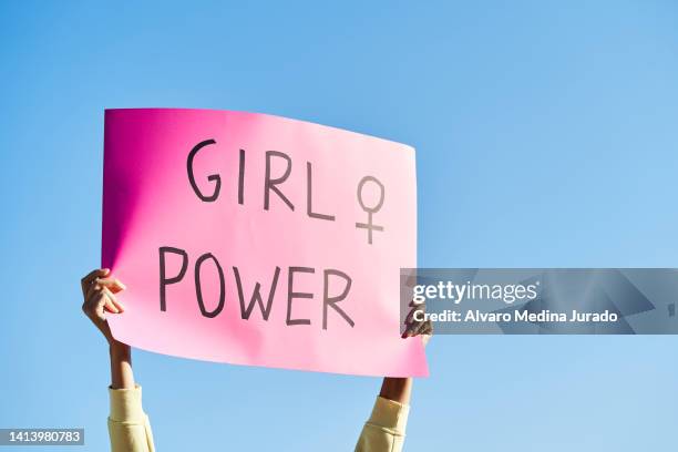 unrecognizable woman's hands holding a protest banner with the message girl power, with the blue sky in the background. - womens rights stock-fotos und bilder