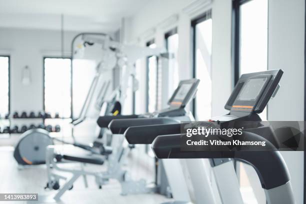 row of treadmills for running exercises in modern fitness center - aparatos para hacer ejercicio fotografías e imágenes de stock