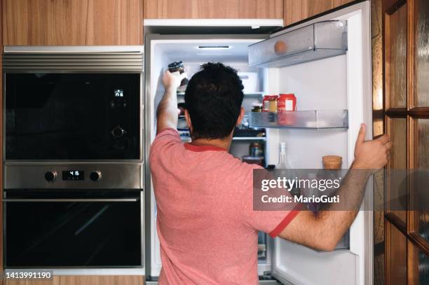 person picking something from inside a refrigerator - young man groceries kitchen stockfoto's en -beelden