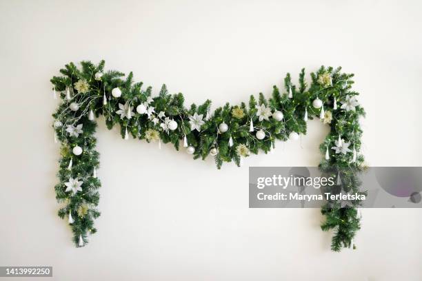 christmas garland with a christmas tree on a white wall. new year's decor. minimalism. festive background. - christmas tree lights stock-fotos und bilder