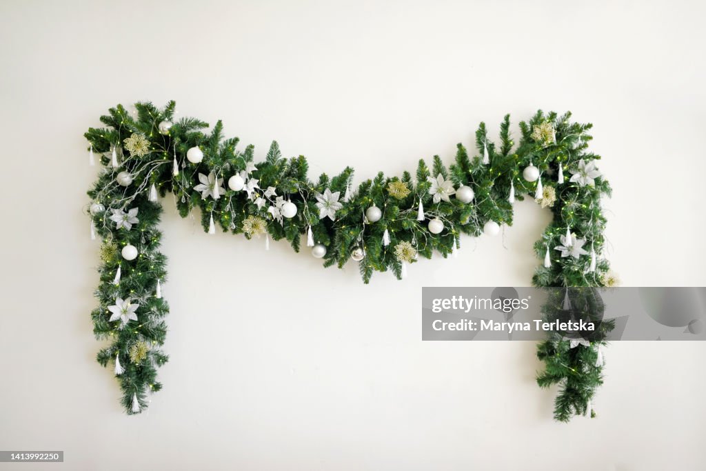 Christmas garland with a Christmas tree on a white wall. New Year's decor. Minimalism. Festive background.