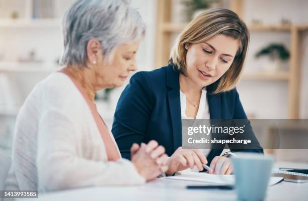 talking financial advisor helping senior with paperwork, retirement budget and managing pension fund. finance worker explaining and showing old woman where to sign will agreement and banking contract - signing document stock pictures, royalty-free photos & images