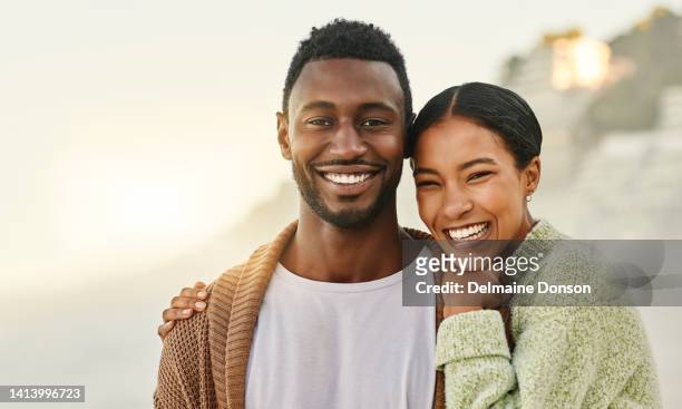 loving and affectionate couple enjoying the weekend together outdoors at the beach and hugging. portrait of a happy african american lovers spending time together on vacation or on holiday - couple outdoors imagens e fotografias de stock