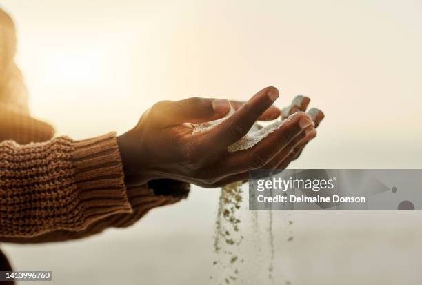 closeup pouring sand through hands on the beach during sunset. man holding or playing with soft soil grains while it runs through fingers outside in nature near the ocean in summer with copy space - calm down stock pictures, royalty-free photos & images