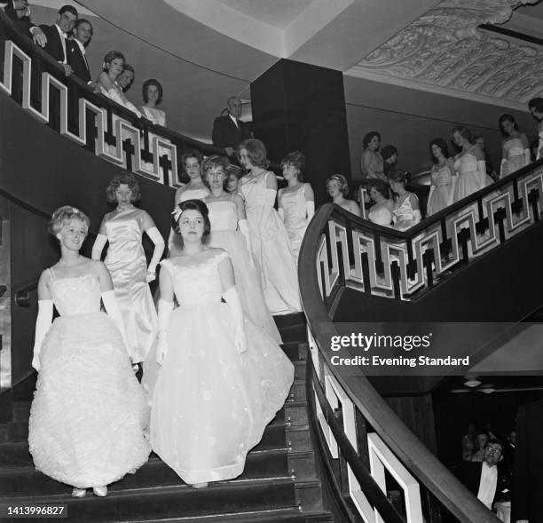 Debutantes attend an debutante ball, descending a staircase at the Grosvenor House Hotel, in Mayfair, London, England, 2nd May 1962. This is possibly...