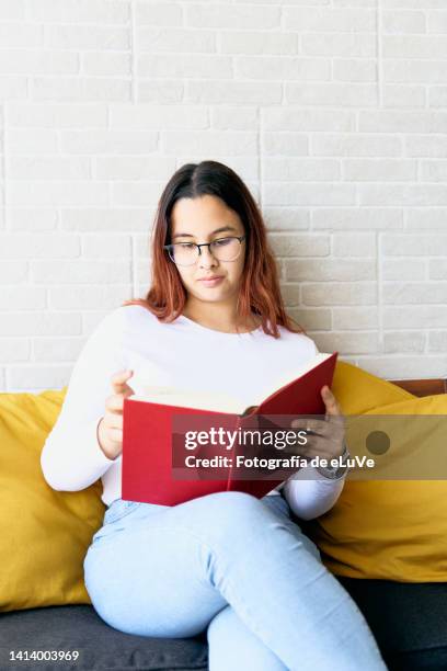 teenage girl reading and turning page of a red book - e girls stock pictures, royalty-free photos & images