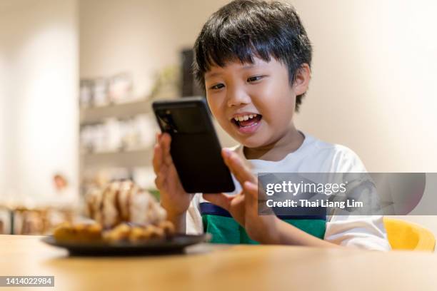 un garçon utilisant un smartphone prenant des photos de son dessert dans un restaurant - child foodie photos et images de collection