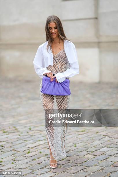 Guest wears rhinestones and black sunglasses, a white cropped shirt, a silver rhinestones / fishnet / mesh / V-neck / long slit dress, a purple shiny...