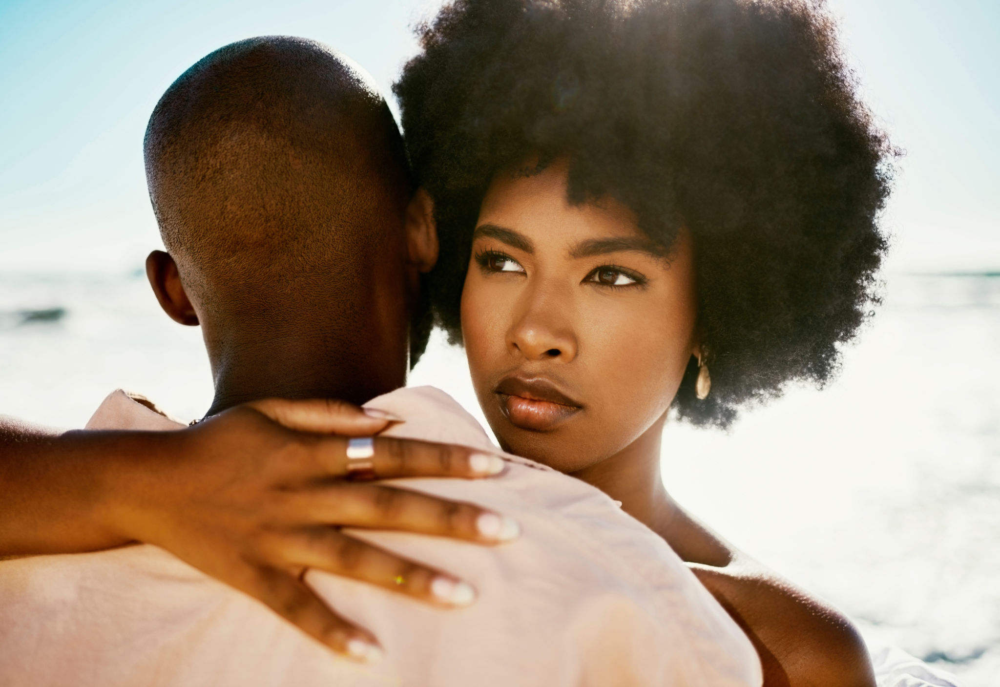 African couple hugging, pensive girl looking in the distance while touching her boyfriend outside. Young feminine afro woman in doubt holding her man while thinking about her relationship problems African couple hugging, pensive girl looking in the distance while touching her boyfriend outside. Young feminine afro woman in doubt holding her man while thinking about her relationship problems