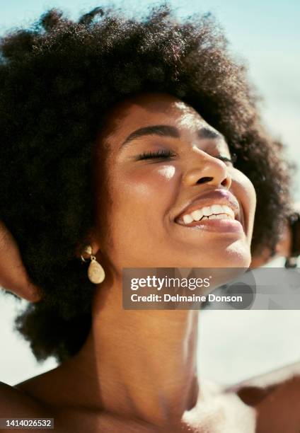 cabeza de mujer feliz, relajada y despreocupada disfrutando del sol en su rostro mientras está de pie afuera con los hombros desnudos. hermosa, sexy y atractiva mujer africana con afro sonriendo y siendo alegre - beautiful bare women fotografías e imágenes de stock