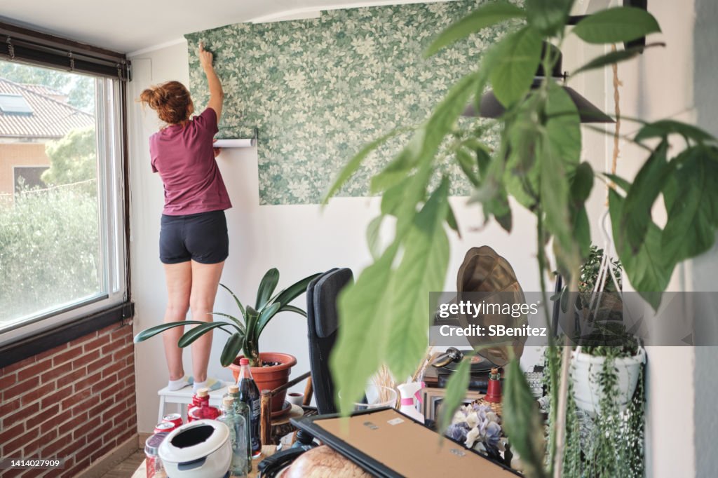 Woman hanging wallpaper