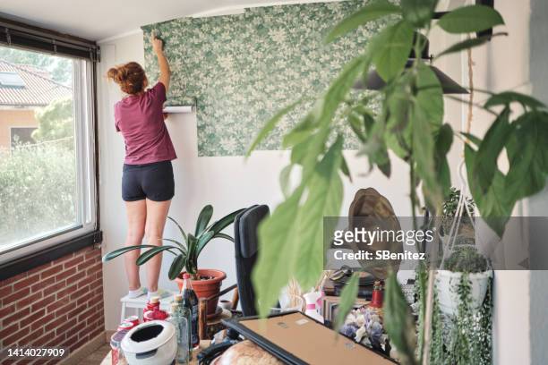 woman hanging wallpaper - decorating stock pictures, royalty-free photos & images