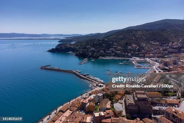 high angle view of townscape by sea against clear sky,porto santo stefano,italy - grosseto province stock pictures, royalty-free photos & images