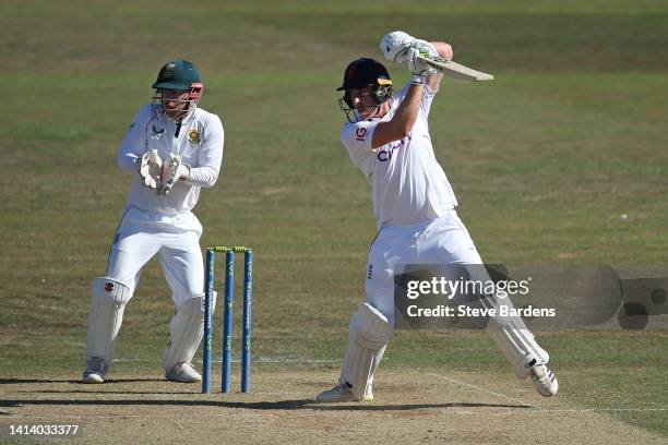 Dan Lawrence of England Lions hits a boundary for four as Kyle Verreynne of South Africa looks on during day two of the tour match between England...