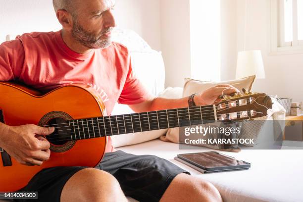 mature man learning to tune the guitar online. - guitar stock pictures, royalty-free photos & images