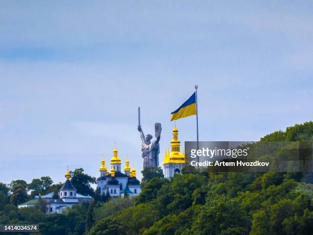 motherland mother monument. statue stands in green hills with kyiv lavra monastery - kiev photos et images de collection