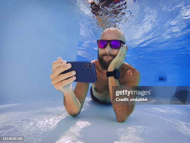 binge watching with mobile phone underwater: social media addiction - crazy pool stock pictures, royalty-free photos & images