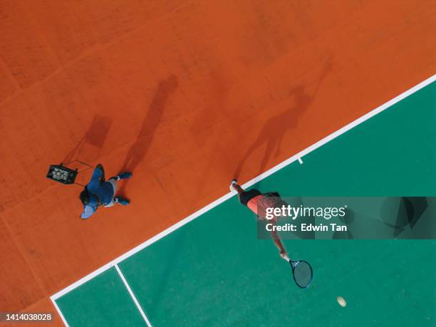 point de vue drone entraînement sportif joueuse de tennis indienne asiatique servant le ballon s’entraînant sur le court de tennis directement au-dessus avec les conseils de l’entraîneur - tennis coaching photos et images de collection