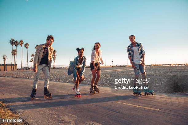 amici pattinaggio a rotelle sulla spiaggia in california - venice beach foto e immagini stock