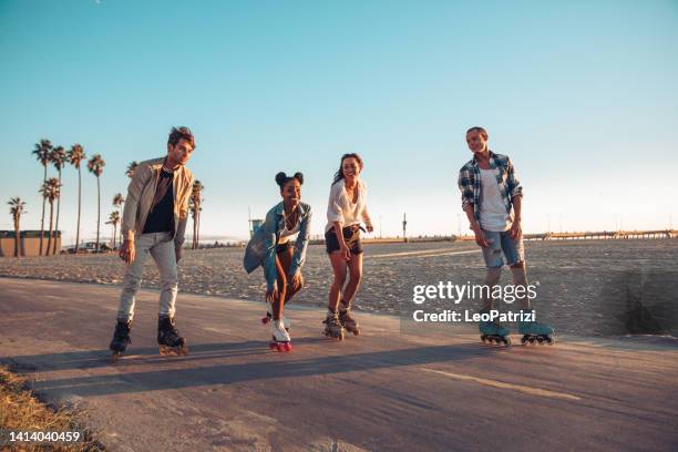friends roller skating by the beach in california - skaten stockfoto's en -beelden