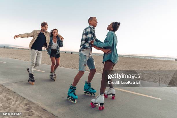 friends roller skating by the beach in california - rolschaatsen schaats stockfoto's en -beelden