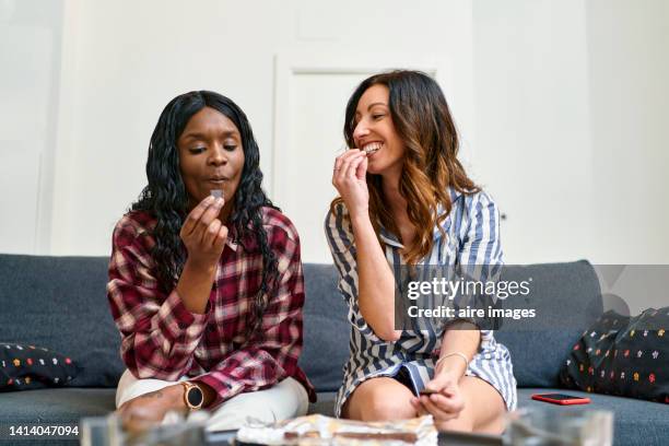 friends talking quietly and happily sharing a chocolate bar in the living room of a house. - chocolate bar stock-fotos und bilder