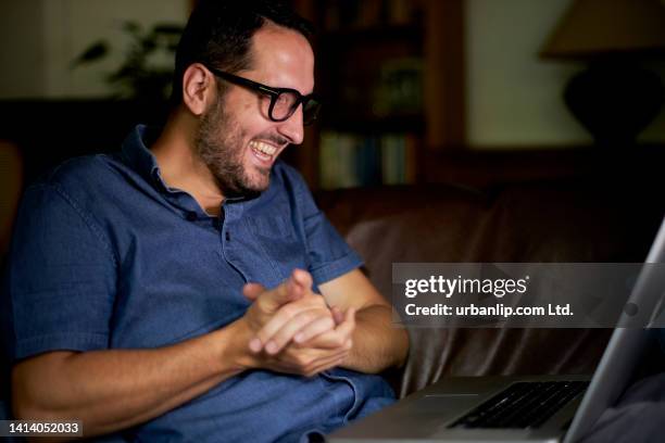 happy man rubbing his hands together whilst watching his laptop screen - rubbing hands together stock pictures, royalty-free photos & images