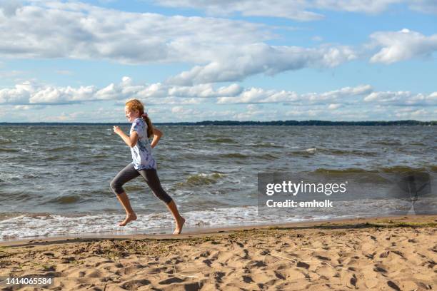 風の日にビーチで走る少女 - barefoot redhead ストックフォトと画像