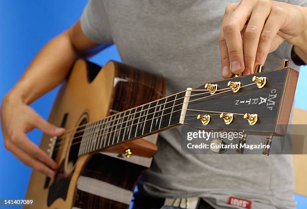 Close-up of a man tuning an acoustic guitar, during a studio shoot for Guitarist Magazine/Future via Getty Images, July 27, 2010.