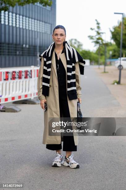 Karla Jenders is seen wearing trench coat, black white striped jumper, black pants, sneaker, bag outside Remain during Copenhagen Fashion Week...