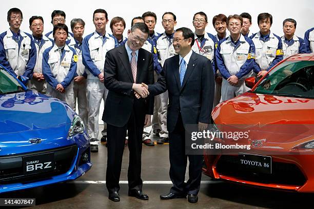 Yasuyuki Yoshinaga, president of Fuji Heavy Industries Ltd., front left, and Akio Toyoda, president of Toyota Motor Corp., shake hands as they pose...