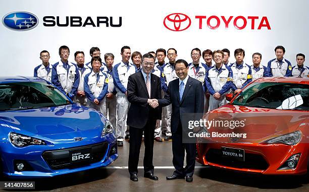 Yasuyuki Yoshinaga, president of Fuji Heavy Industries Ltd., front left, and Akio Toyoda, president of Toyota Motor Corp., shake hands as they pose...