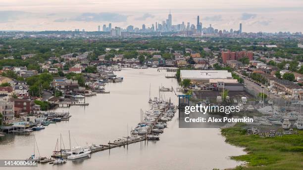 manhattan over brooklyn distant view, east mill bassin with marina at the front with many yachts and boats. neighborhoods old mill bassin, flatlands and bergen beach. - long island stockfoto's en -beelden