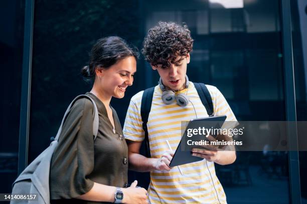 portrait of a couple of students standing and using the digital tablet - couple school stockfoto's en -beelden