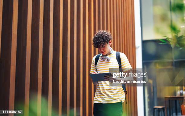 handsome young man walking and using the tablet - cladding stock pictures, royalty-free photos & images