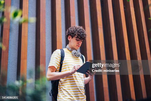 handsome young man walking and using the tablet - cladding stockfoto's en -beelden