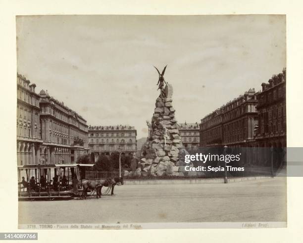 Monument of pile of stones and an angel. Torino Piazza dello Statute col monumento del Frejus The statue stands in field, screened by fence and is...