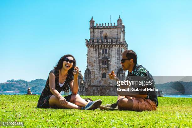 friends sitting on grass eating a pastel de nata - voyageur homme devant monument photos et images de collection
