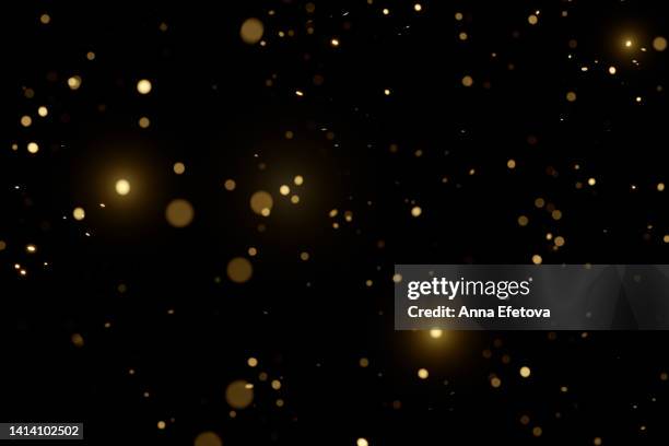 blurred golden particles on black background. holiday background. festive colorful backdrop for your design. merry christmas and happy new year - glitter black background stockfoto's en -beelden