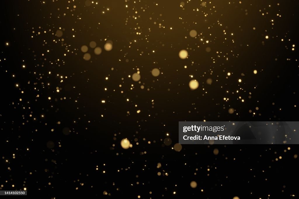 Glittering golden particles on black isolated background. Christmas and New Year concept in trendy festive golden color