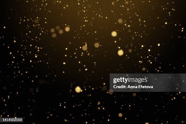 glittering golden particles on black isolated background. christmas and new year concept in trendy festive golden color - particle 個照片及圖片檔