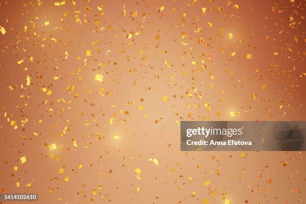 many flying golden confetti on beige background. festive backdrop for your products presentation. copy space for your design. merry christmas and happy new year celebration concept - 授賞式 ストックフォトと画像