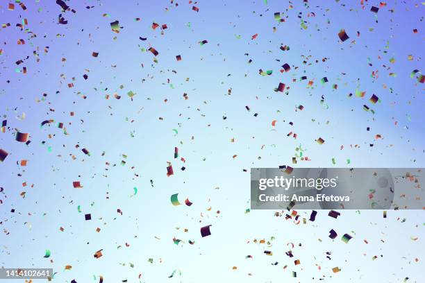 paper multicolored confetti on light blue background. festive backdrop for your products presentation. copy space for your design - first light awards stock-fotos und bilder