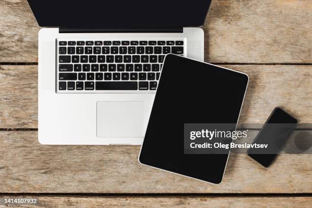 top view of modern gadgets on wooden table. laptop, tablet, mobile phone. - notepad table stockfoto's en -beelden